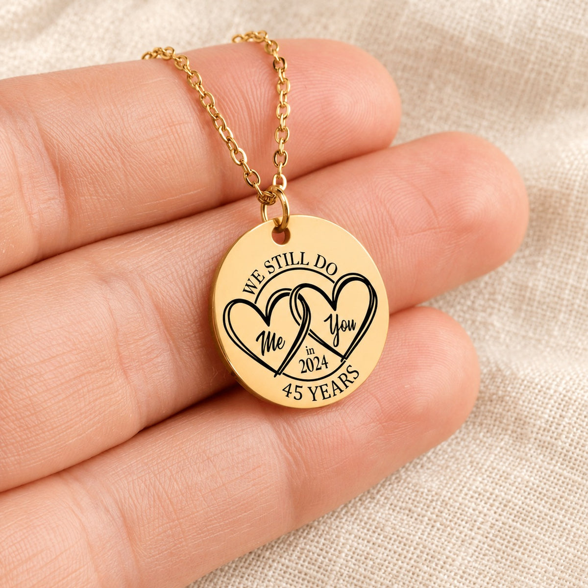 Collier Médaille Anniversaire de Mariage 45 ans doré tenu en main, détail de la gravure.