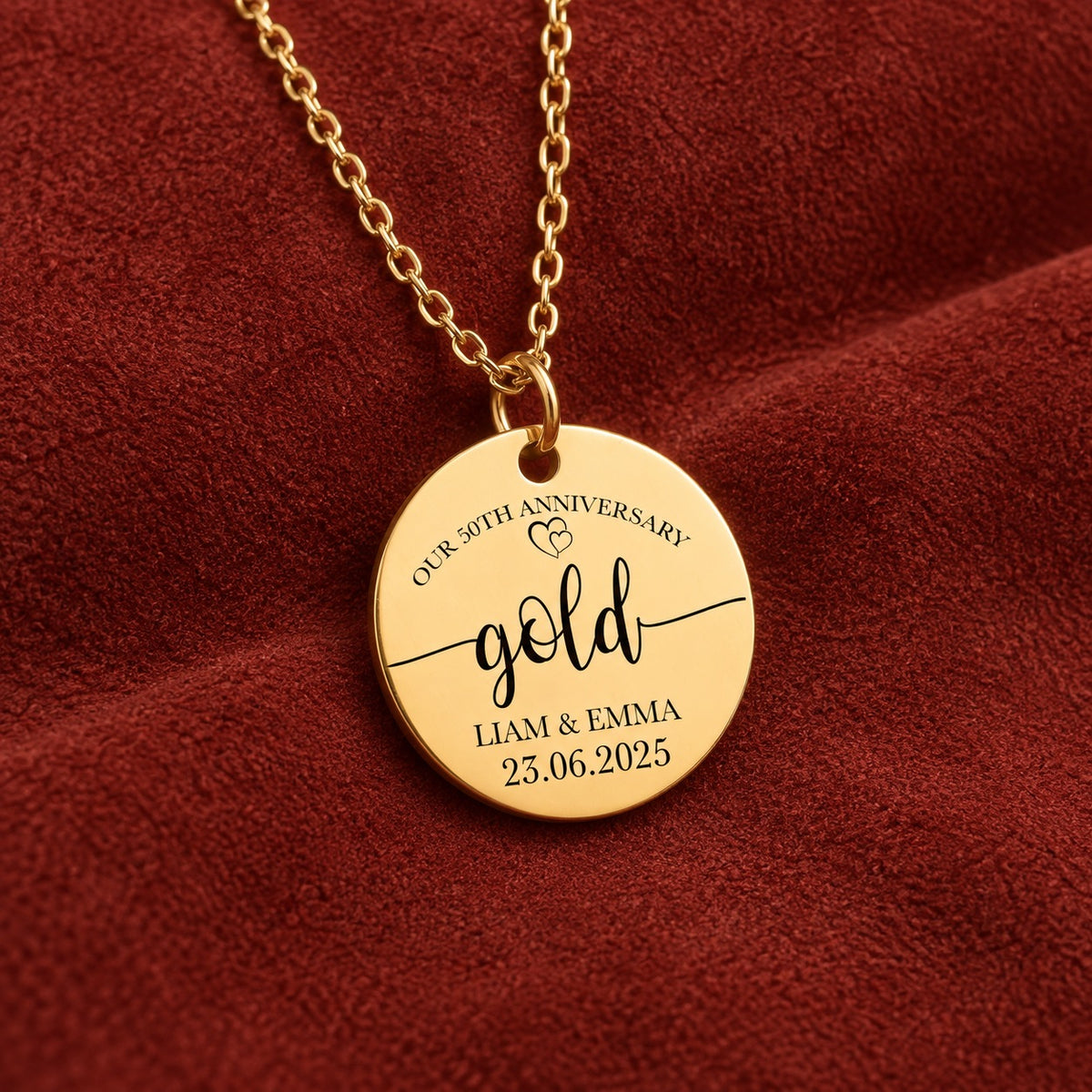 Médaille ronde dorée avec inscription « gold », prénoms Liam et Emma et date 23.06.2025, sur suédine rouge sanguine.