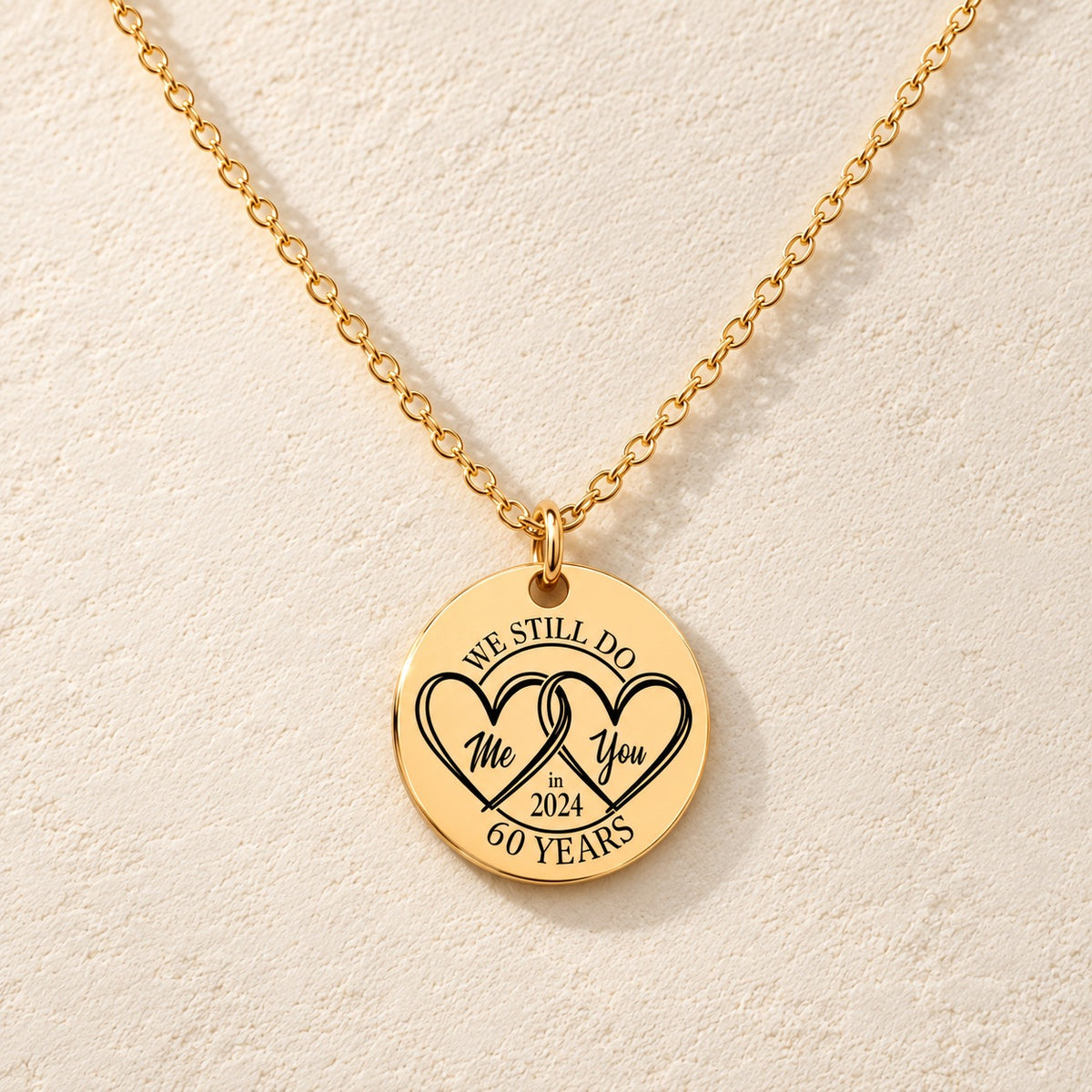 Collier Médaille Anniversaire de Mariage 60 ans doré, médaille ronde gravée avec deux cœurs et inscription « 60 YEARS », sur fond ivoire.