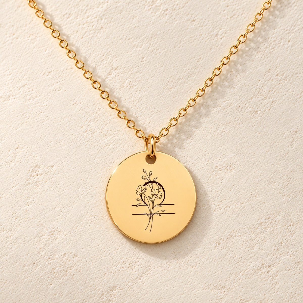Collier médaille florale signe astrologique Balance doré, médaille ronde gravée avec symbole du signe Balance et fleurs, sur fond ivoire.
