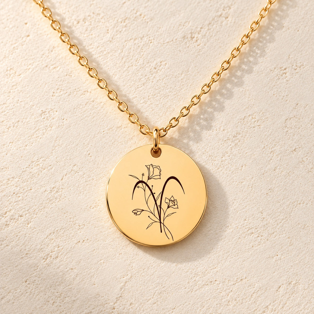 Détail de la médaille ronde dorée avec symbole du signe Bélier et fleurs.