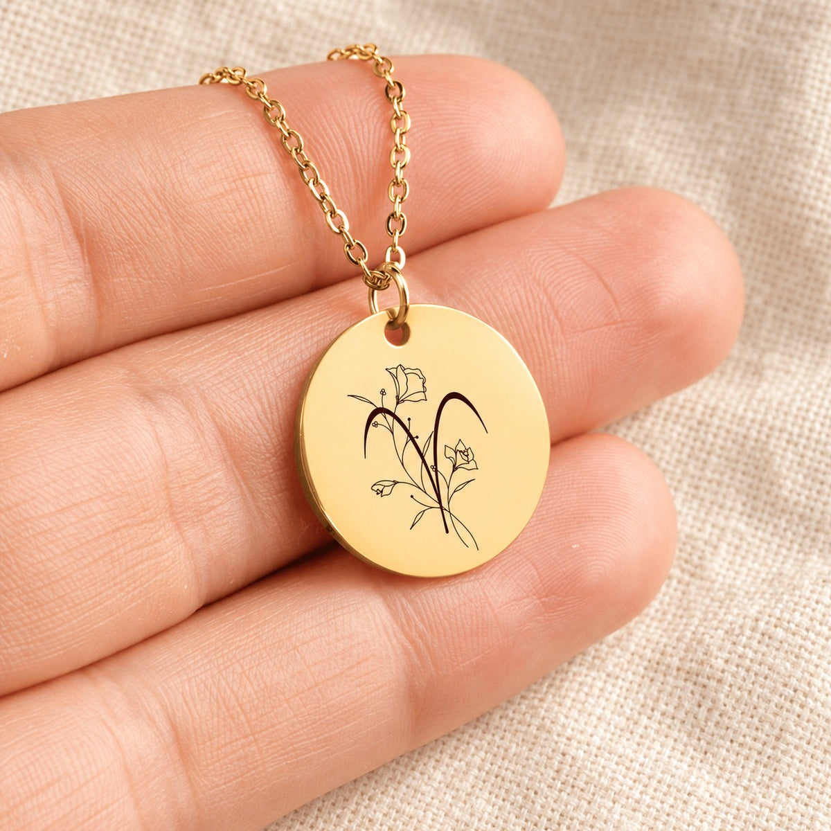 Collier médaille florale signe astrologique Bélier doré tenu en main, détail de la gravure.
