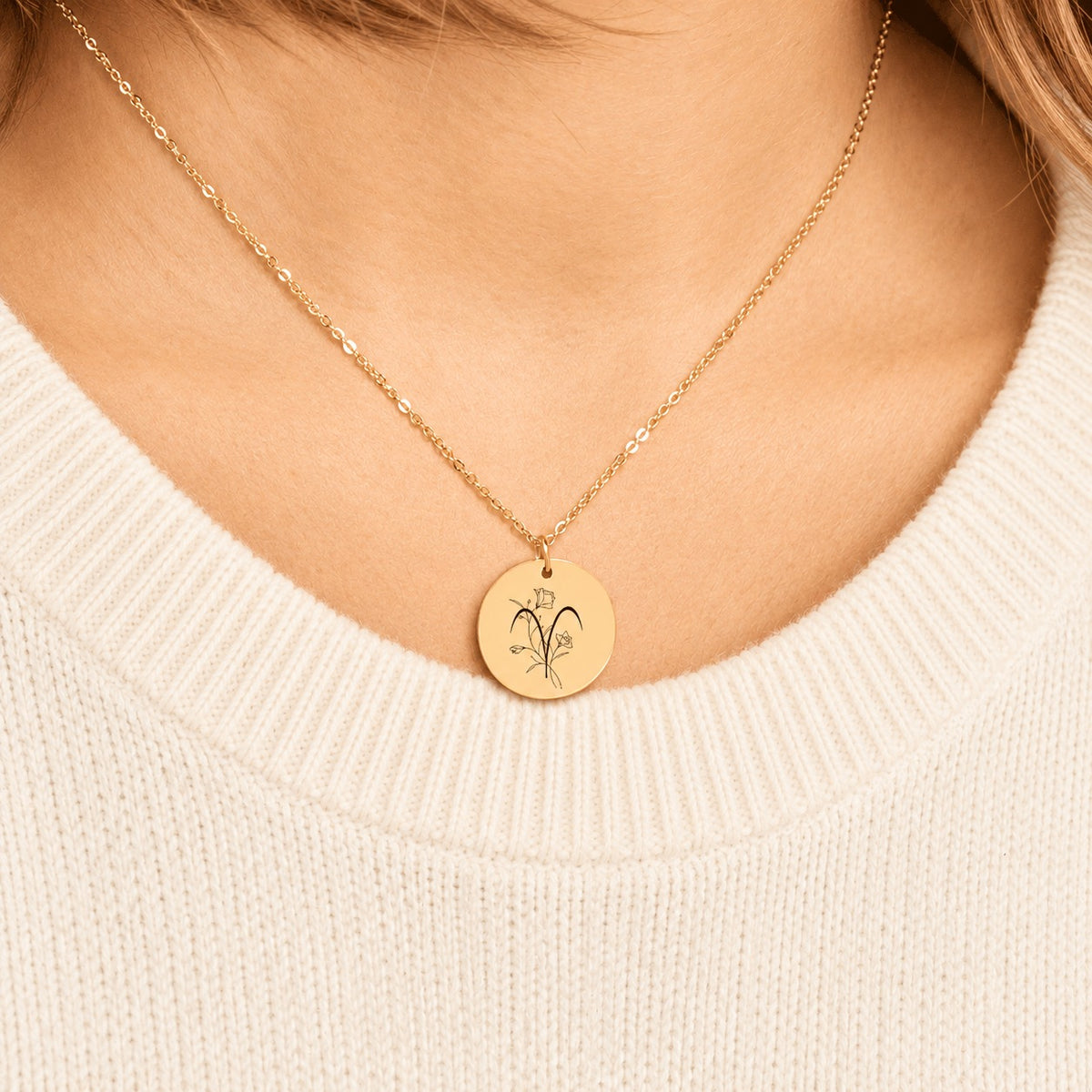 Collier médaille florale signe astrologique Bélier doré porté au cou, médaille ronde gravée.