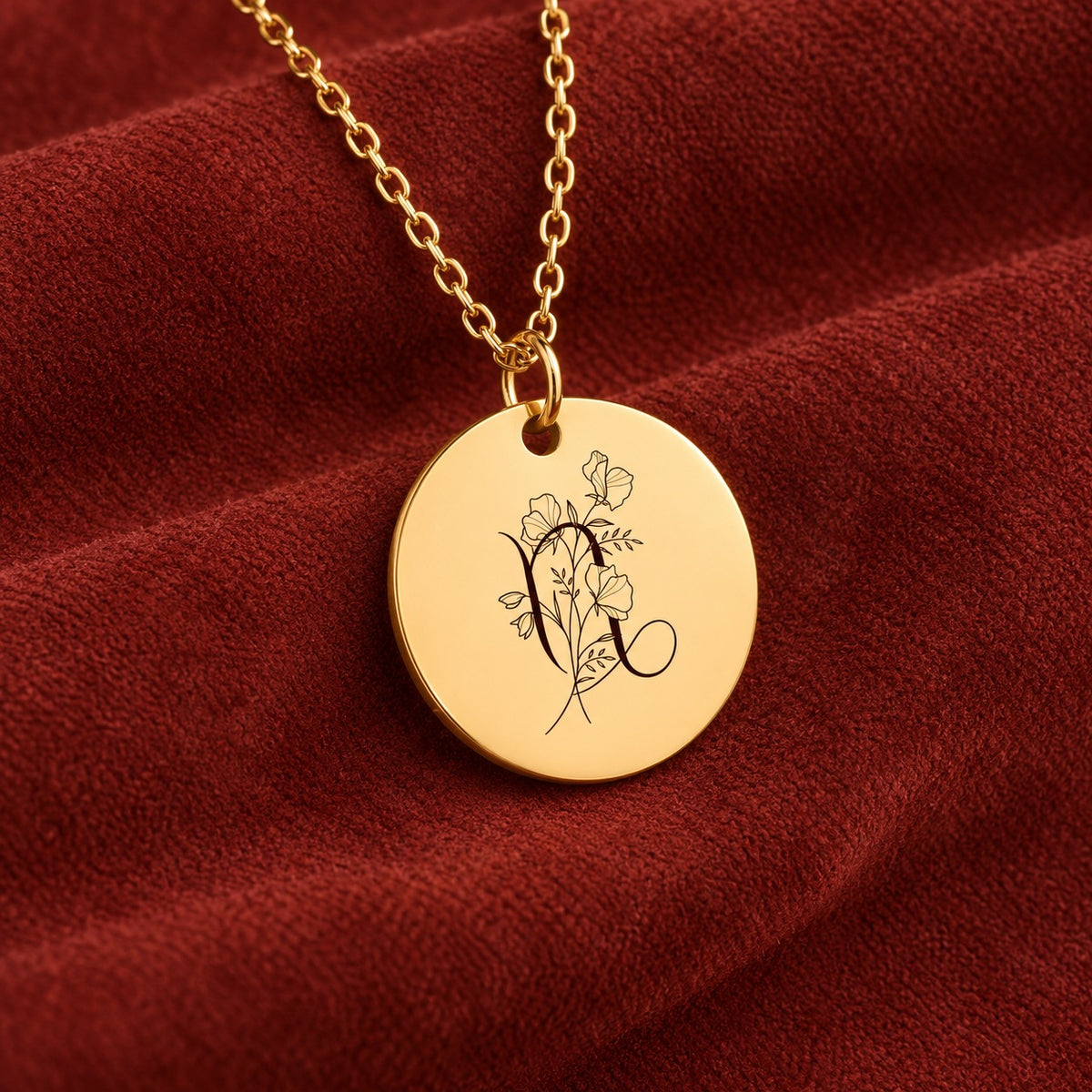 Médaille ronde dorée avec symbole du signe Capricorne et fleurs, sur suédine rouge sanguine.