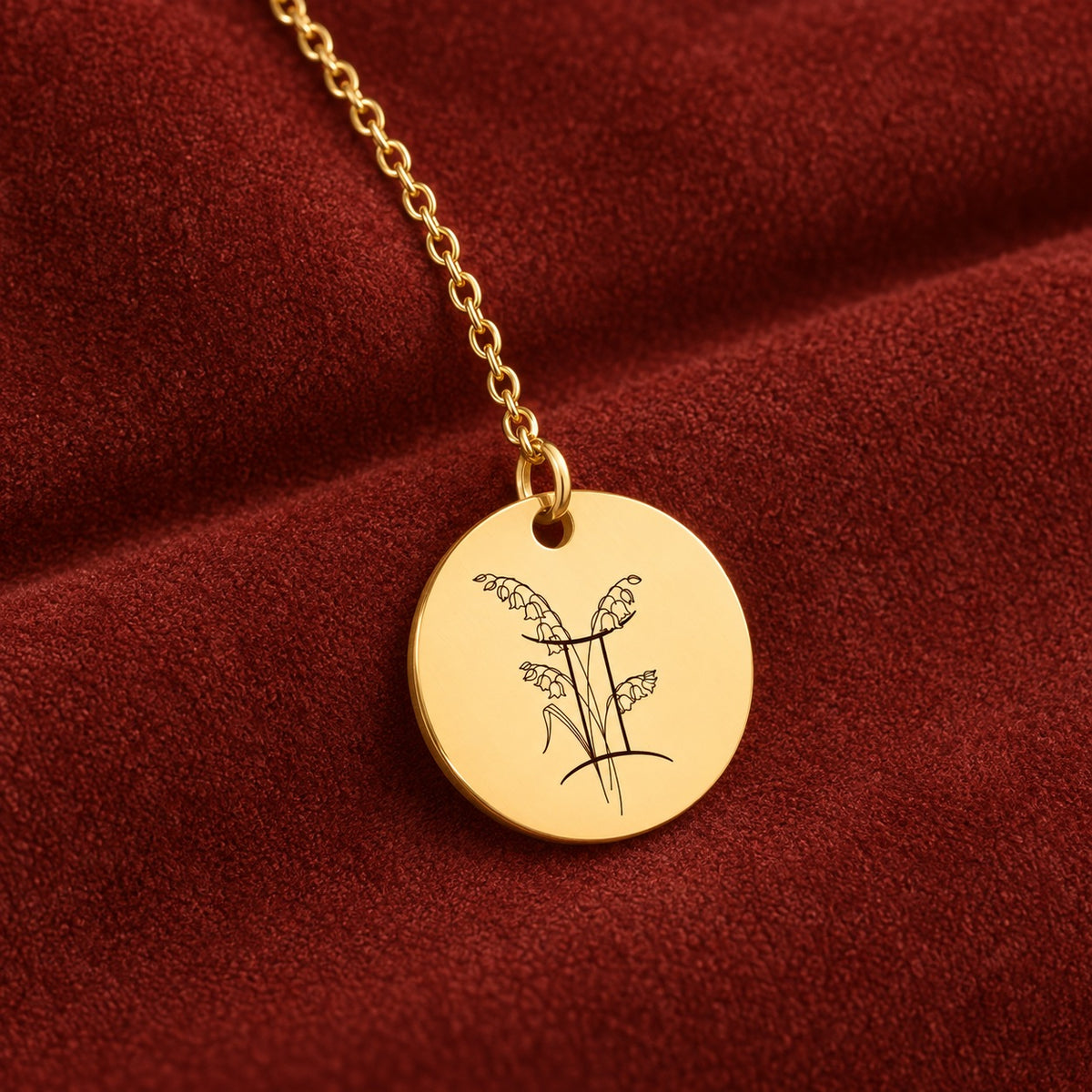 Médaille ronde dorée avec symbole du signe Gémeaux et fleurs, sur suédine rouge sanguine.