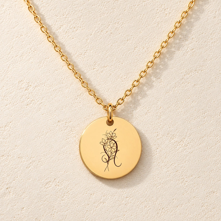 Collier médaille florale signe astrologique Lion doré, médaille ronde gravée avec symbole du signe Lion et fleurs, sur fond ivoire.