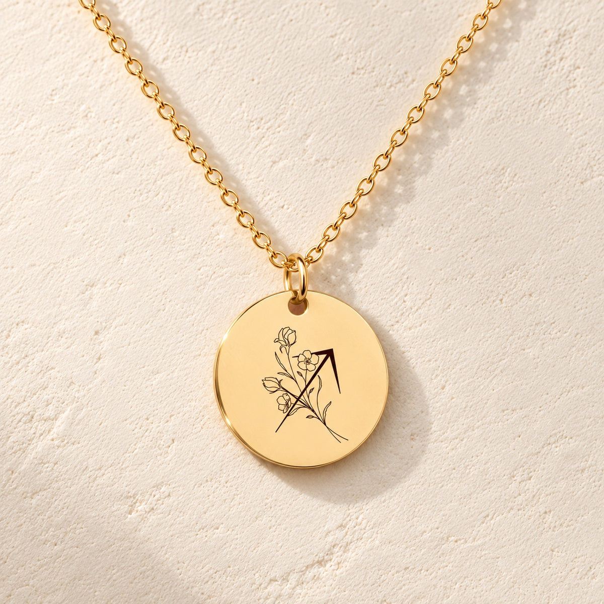 Détail de la médaille ronde dorée avec symbole du signe Sagittaire et fleurs.