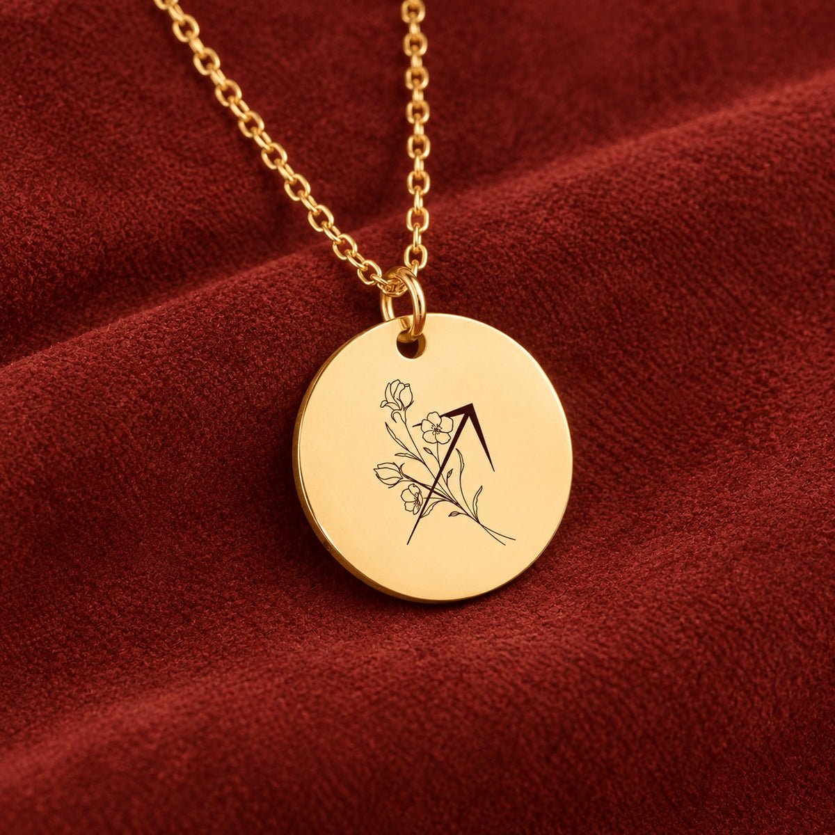 Médaille ronde dorée avec symbole du signe Sagittaire et fleurs, sur suédine rouge sanguine.