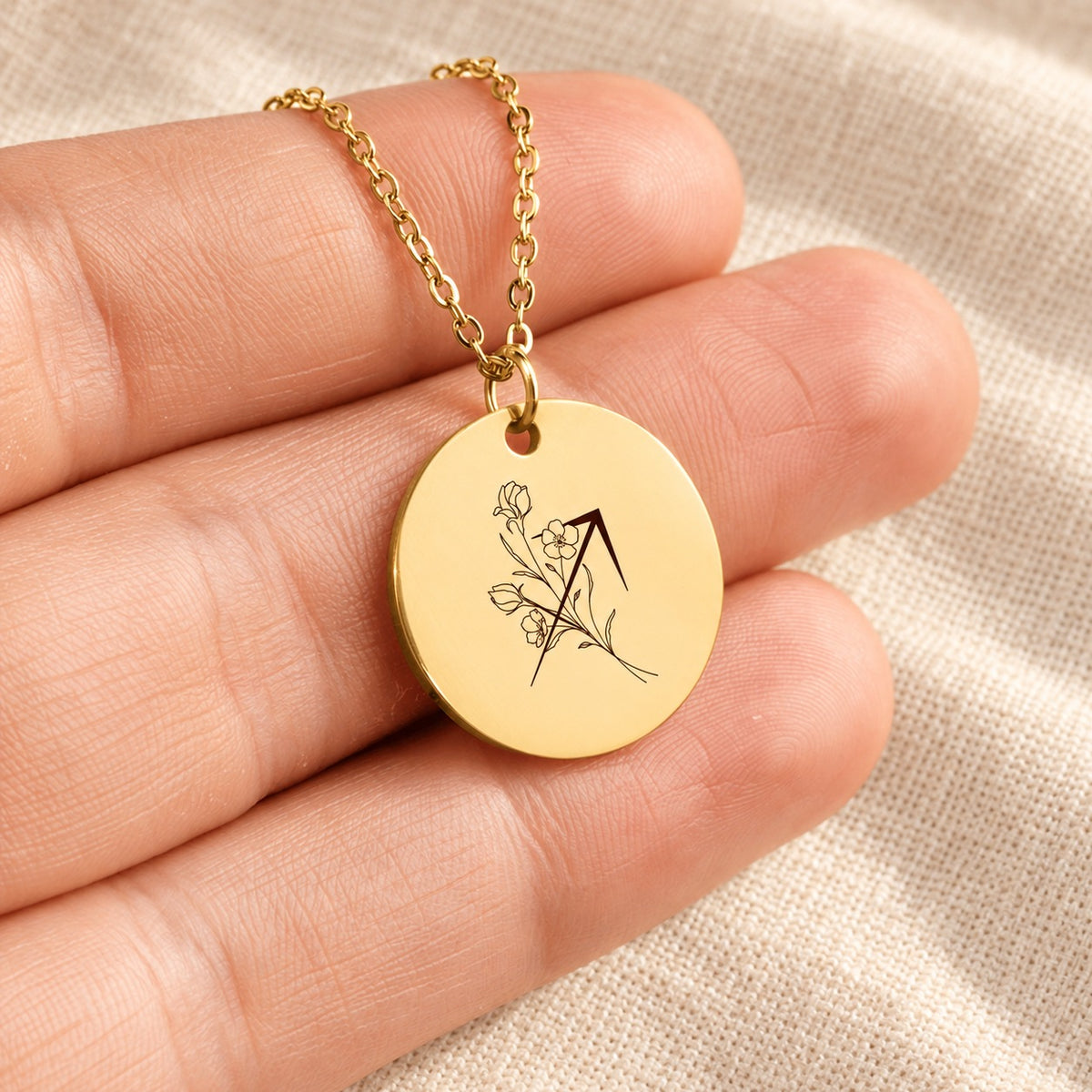 Collier médaille florale signe astrologique Sagittaire doré tenu en main, détail de la gravure.