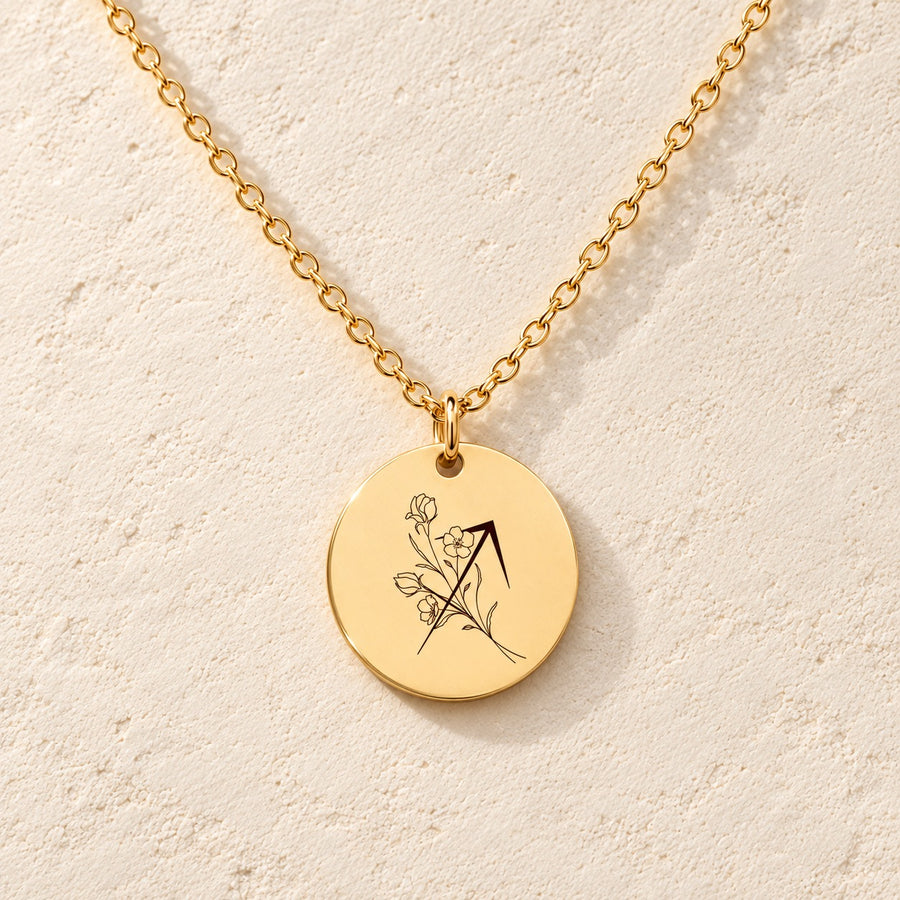 Collier médaille florale signe astrologique Sagittaire doré, médaille ronde gravée avec symbole du signe Sagittaire et fleurs, sur fond ivoire.