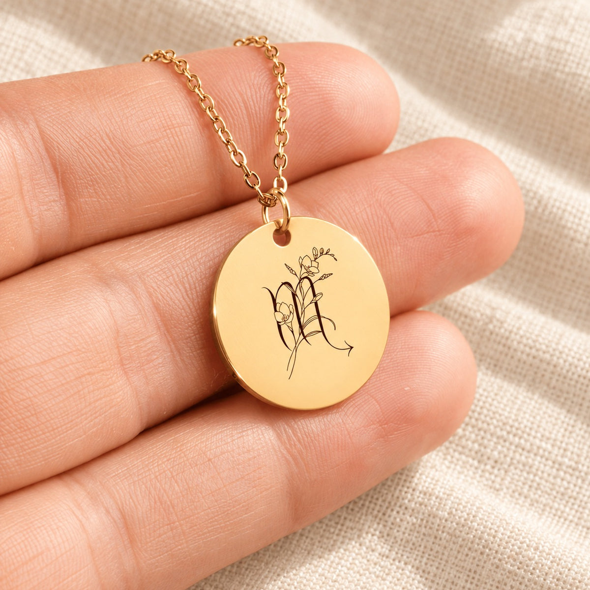 Collier médaille florale signe astrologique Scorpion doré tenu en main, détail de la gravure.