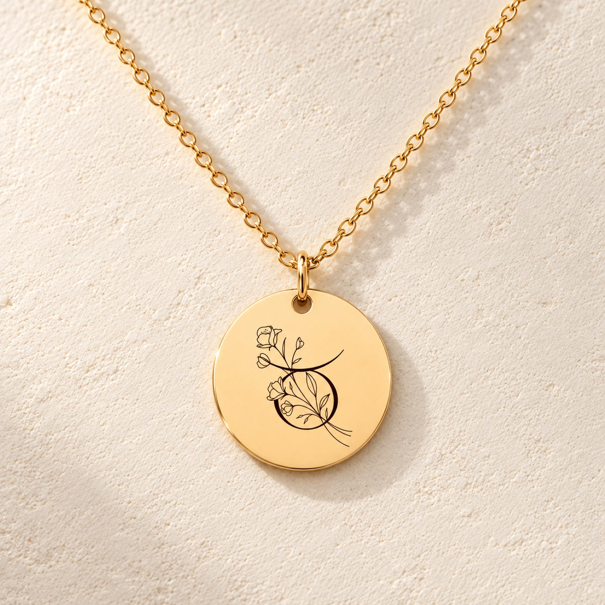 Détail de la médaille ronde dorée avec symbole du signe Taureau et fleurs.