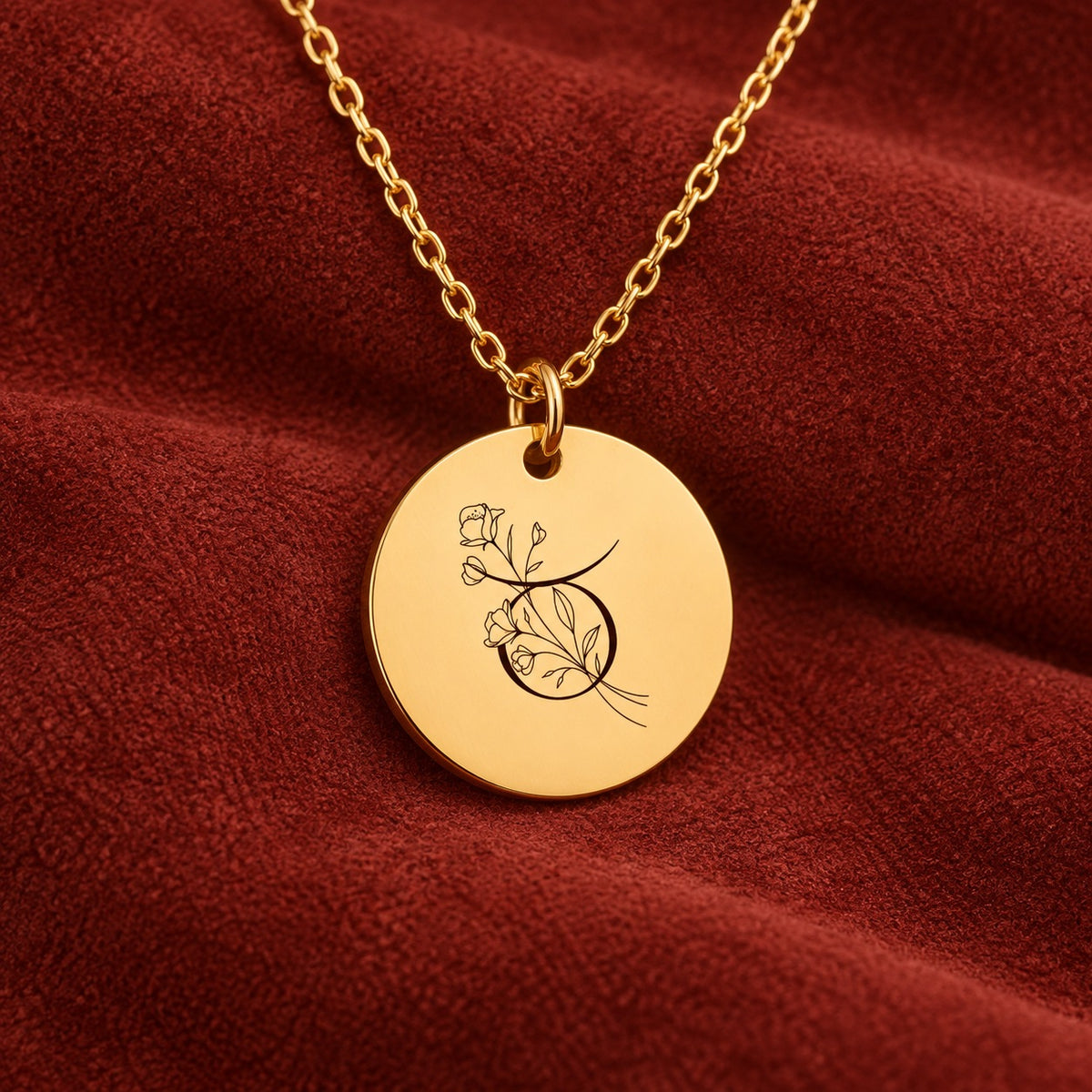Médaille ronde dorée avec symbole du signe Taureau et fleurs, sur suédine rouge sanguine.