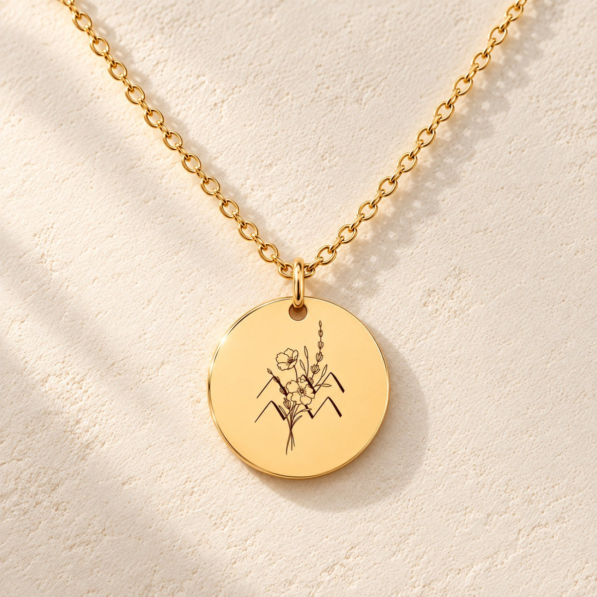 Détail de la médaille ronde dorée avec symbole du signe Verseau et fleurs.