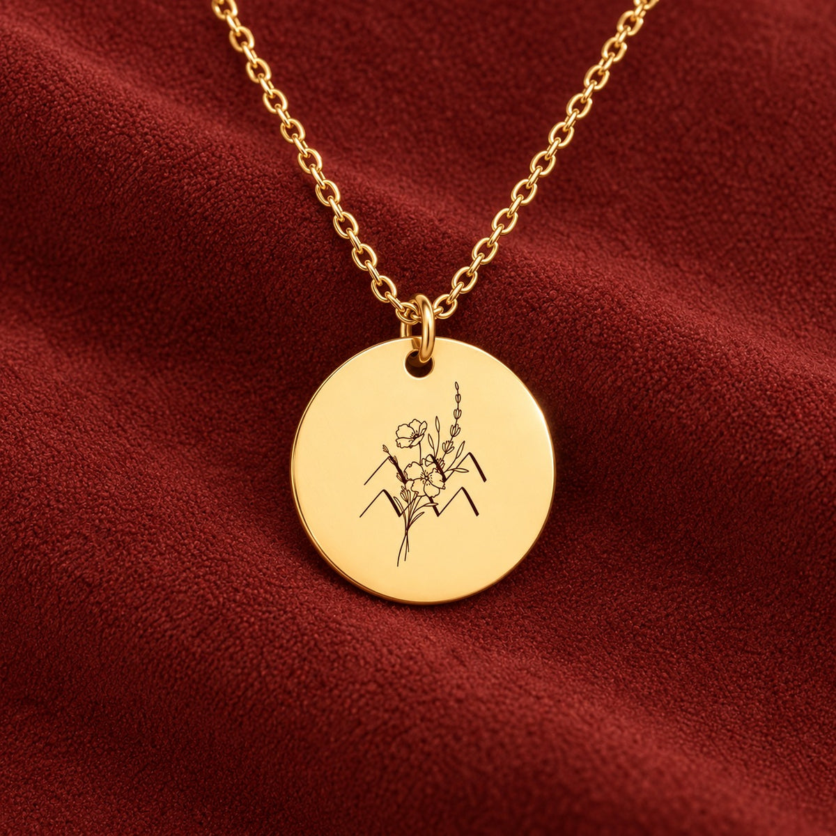 Médaille ronde dorée avec symbole du signe Verseau et fleurs, sur suédine rouge sanguine.