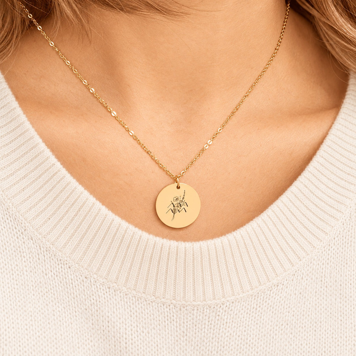 Collier médaille florale signe astrologique Verseau doré porté au cou, médaille ronde gravée.