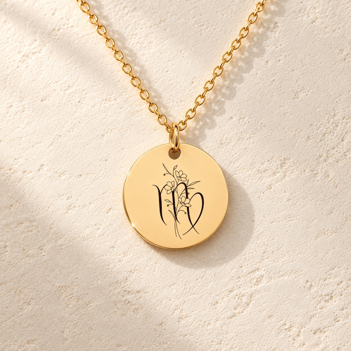 Détail de la médaille ronde dorée avec symbole du signe Vierge et fleurs.