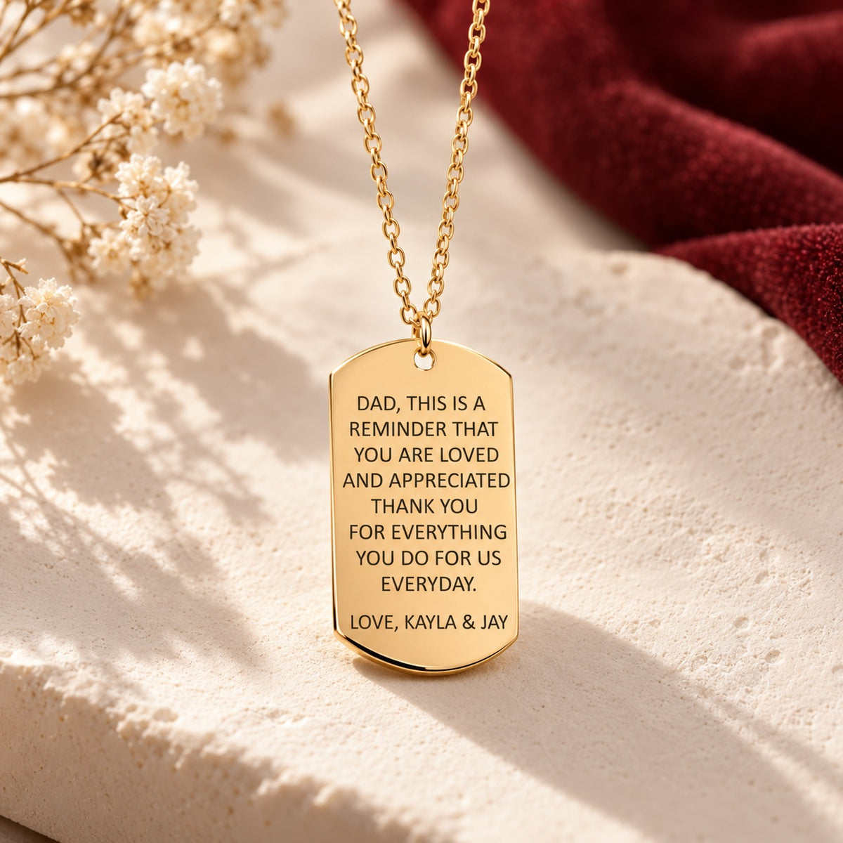 Détail du pendentif doré en forme de plaque, gravé avec message pour papa signé Kayla & Jay.