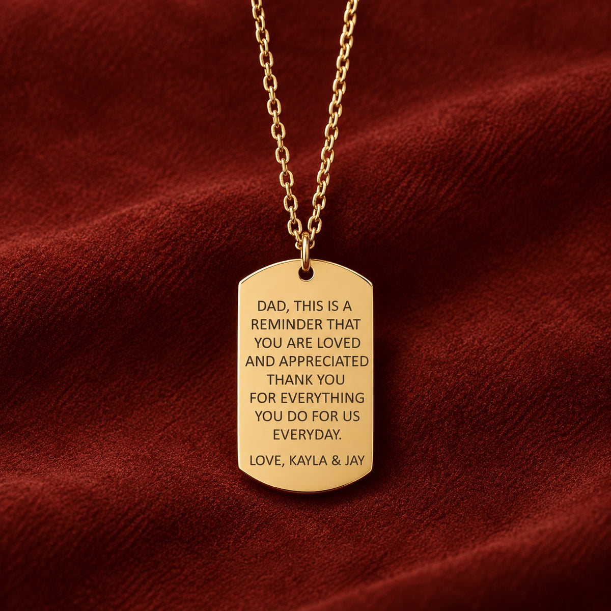 Pendentif doré en forme de plaque, gravé avec message pour papa signé Kayla & Jay sur suédine rouge sanguine.
