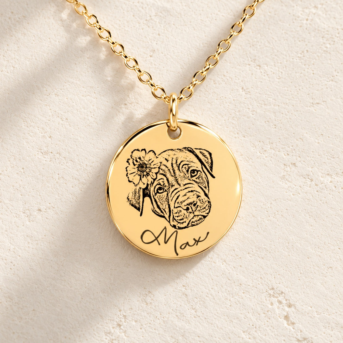 Détail de la médaille dorée du collier personnalisé : portrait de Max, fleur et prénom gravés, sur pierre ivoire.
