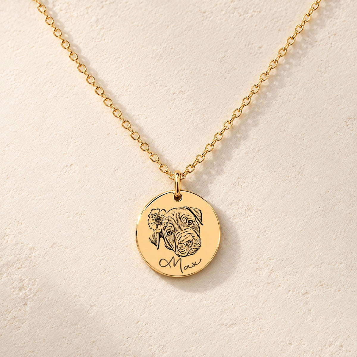 Collier portrait de chien personnalisé doré, médaille ronde gravée du portrait de Max avec une fleur et de son prénom, sur fond ivoire.
