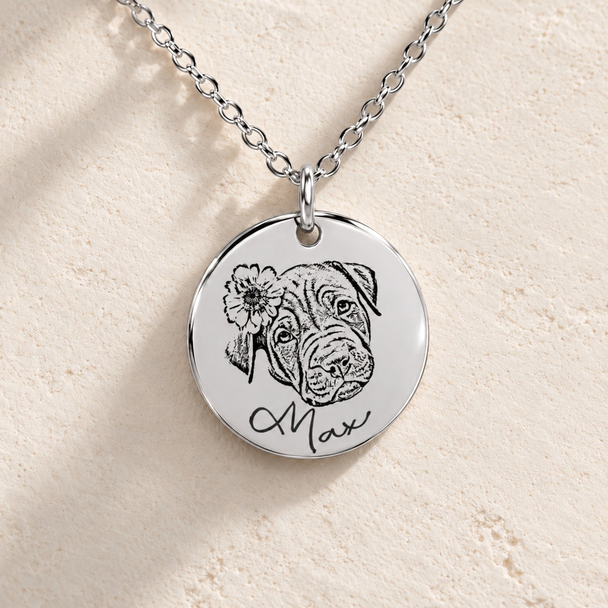 Détail de la médaille argentée du collier personnalisé : portrait de Max, fleur et prénom gravés, sur pierre ivoire.