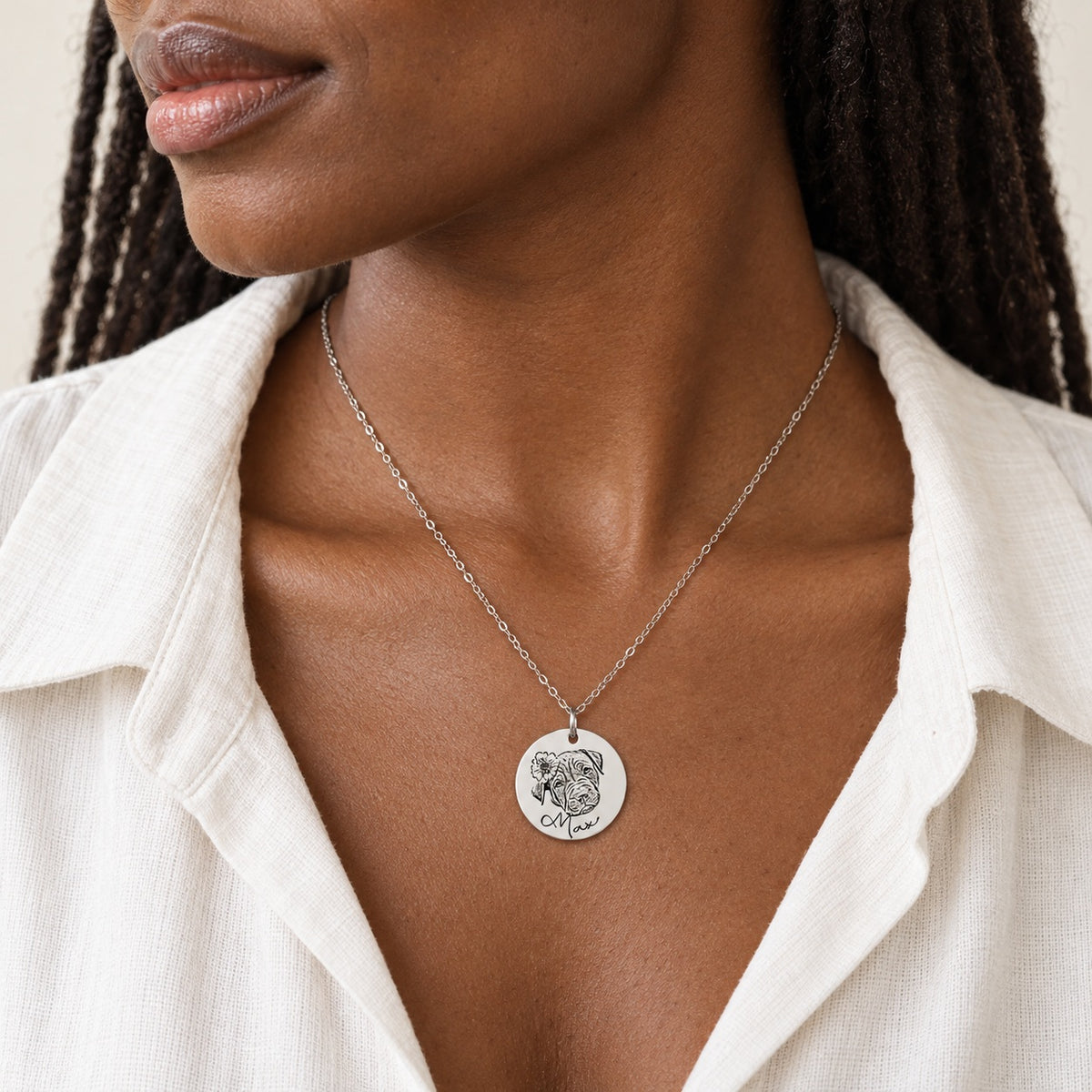 Collier portrait de chien personnalisé argenté porté au cou, avec le portrait fleuri de Max et son prénom gravés sur la médaille ronde.