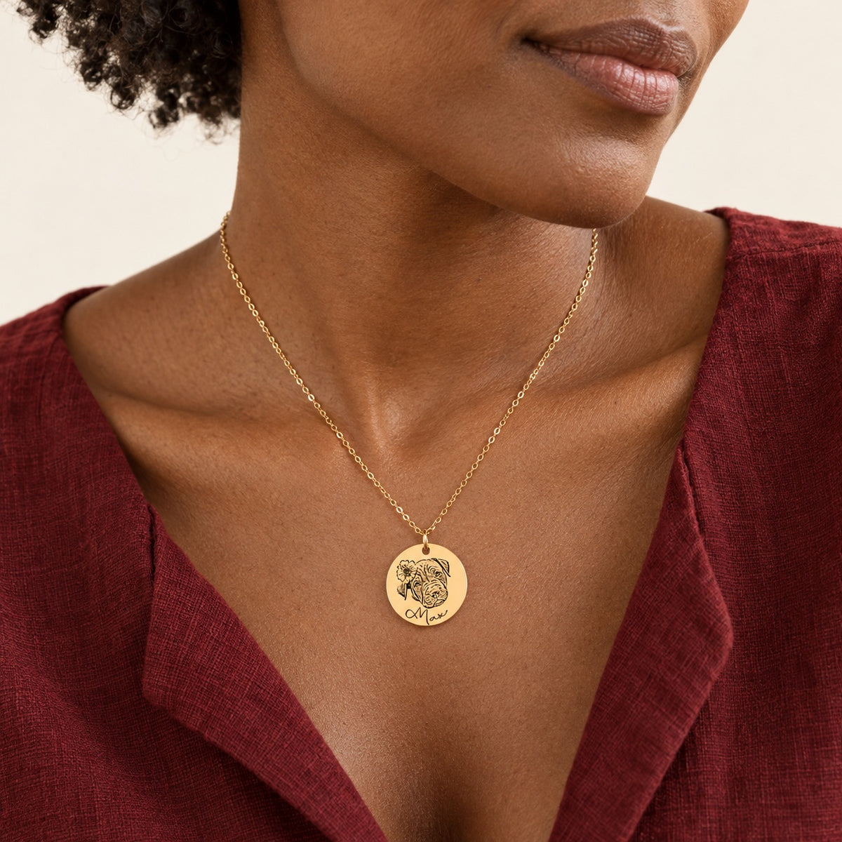 Collier portrait de chien personnalisé doré porté au cou, avec le portrait fleuri de Max et son prénom gravés sur la médaille ronde.