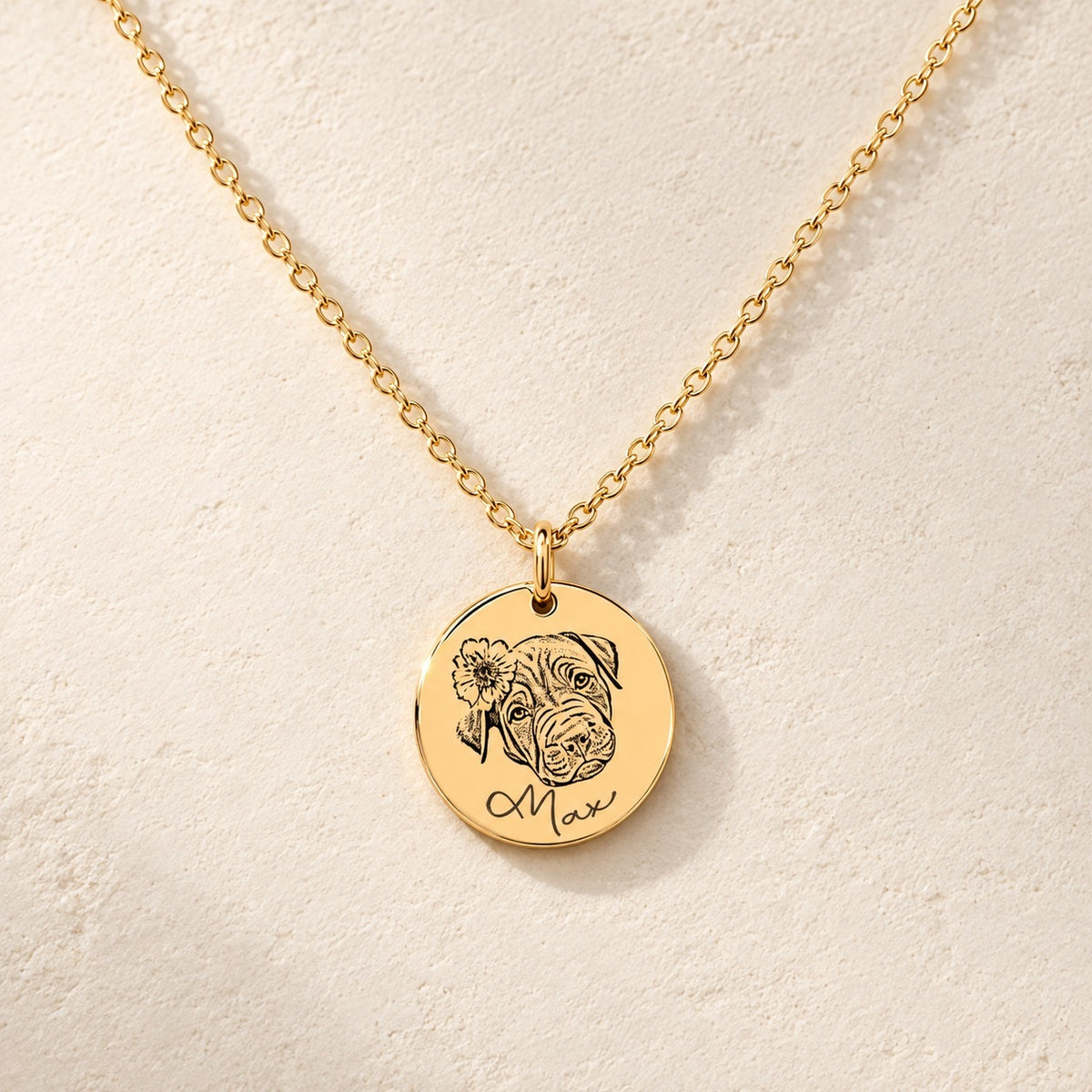 Collier portrait de chien personnalisé doré, médaille ronde gravée du portrait de Max avec une fleur et de son prénom, sur fond ivoire.