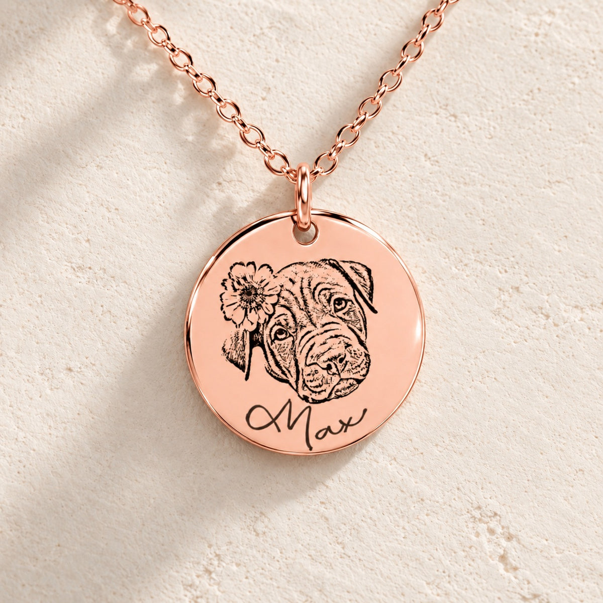 Détail de la médaille en finition or rose du collier personnalisé : portrait de Max, fleur et prénom gravés, sur pierre ivoire.