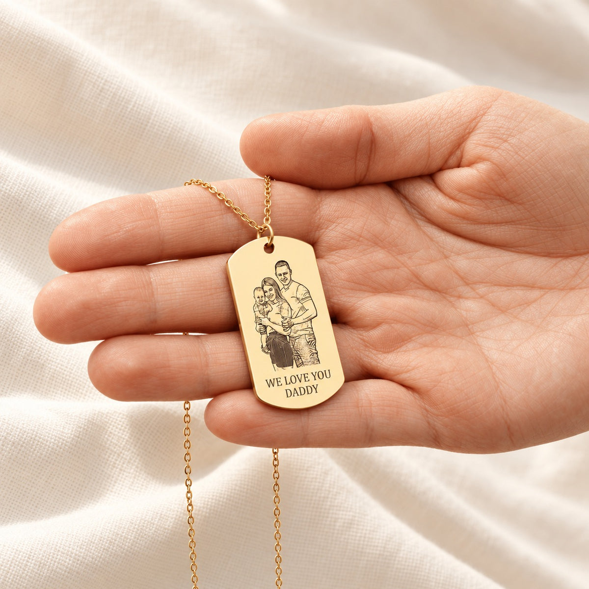 Collier Portrait Personnalisé doré présenté dans une main, avec pendentif rectangulaire gravé.