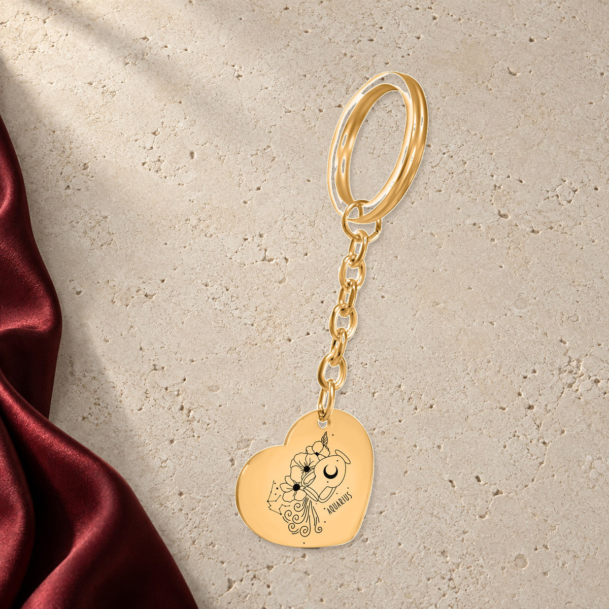 Porte-clés Coeur Signe Astrologique Verseau en finition dorée sur pierre claire, avec étoffe rouge sanguine ; exemple de personnalisation.