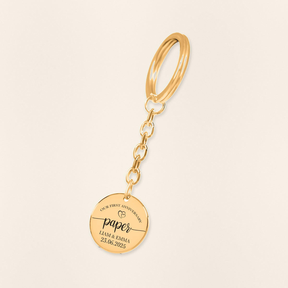 Porte-clés Médaille Anniversaire de Mariage 1 an (noces de coton) en finition dorée, exemple de gravure sur fond ivoire texturé.