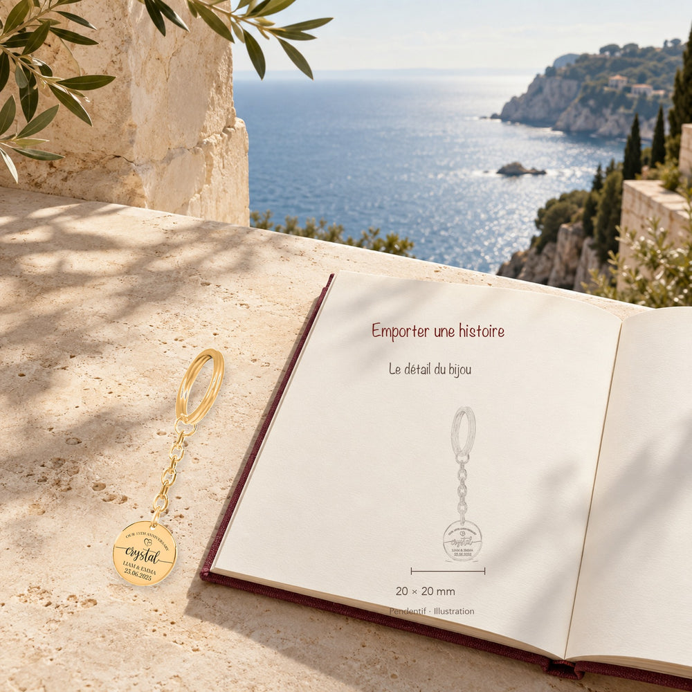 Porte-clés Médaille Anniversaire de Mariage 15 ans (noces de cristal) en finition dorée dans un décor méditerranéen, avec dessin du produit sur un carnet.