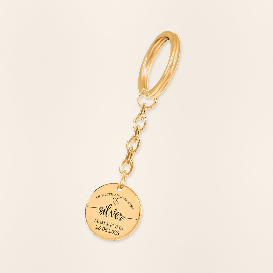 Porte-clés Médaille Anniversaire de Mariage 25 ans (noces d'argent) en finition dorée, exemple de gravure sur fond ivoire texturé.