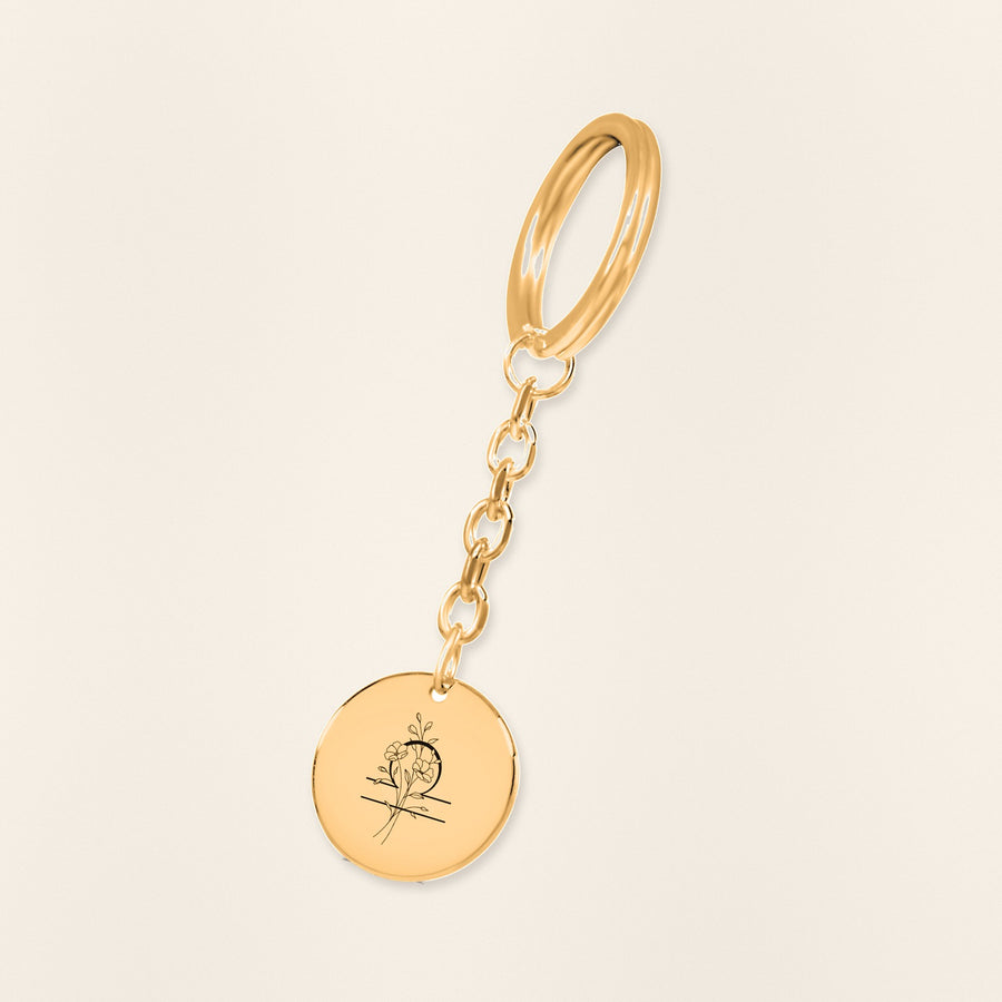 Porte-clés Médaille Florale Signe Astrologique Balance en finition dorée, exemple de gravure sur fond ivoire texturé.