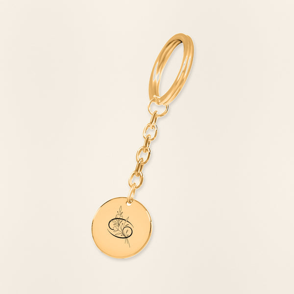 Porte-clés Médaille Florale Signe Astrologique Cancer en finition dorée, exemple de gravure sur fond ivoire texturé.
