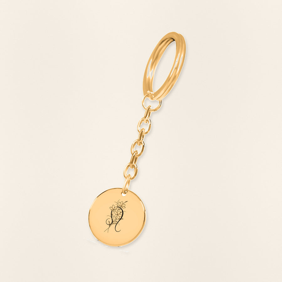 Porte-clés Médaille Florale Signe Astrologique Lion en finition dorée, exemple de gravure sur fond ivoire texturé.