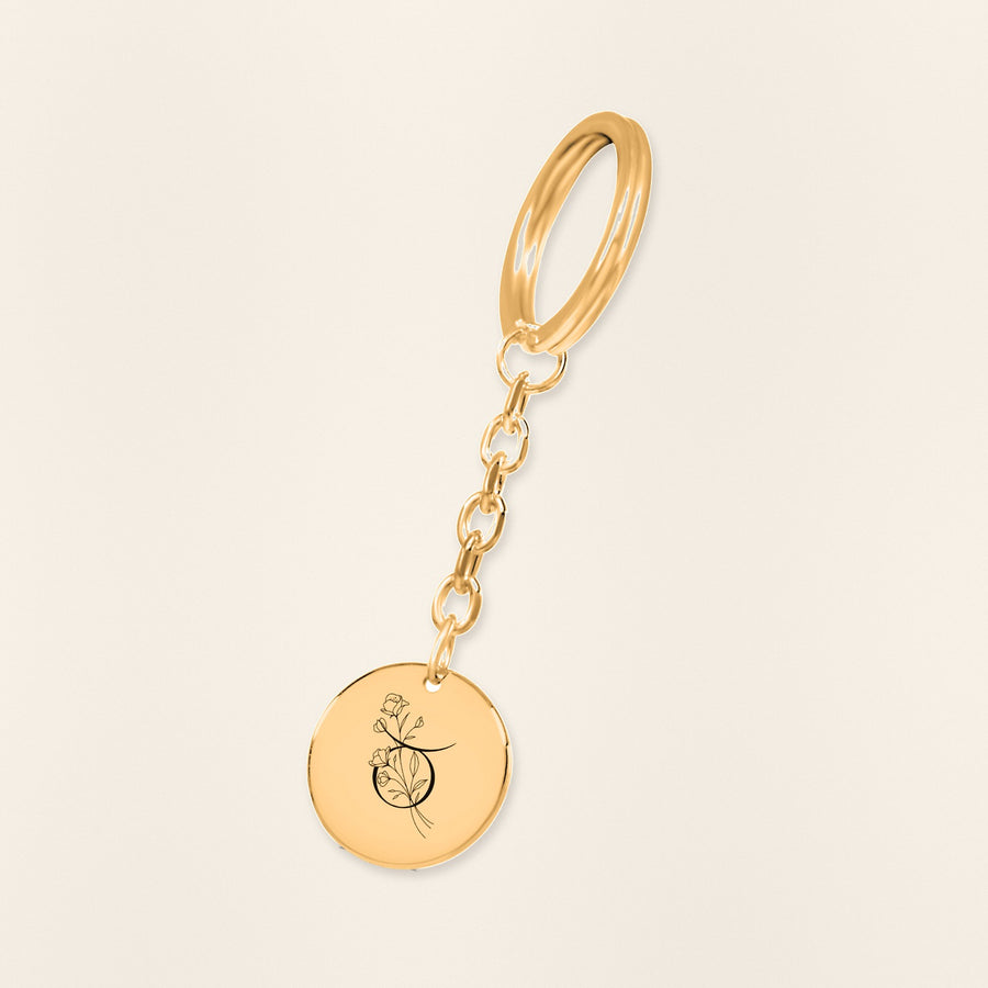 Porte-clés Médaille Florale Signe Astrologique Taureau en finition dorée, exemple de gravure sur fond ivoire texturé.