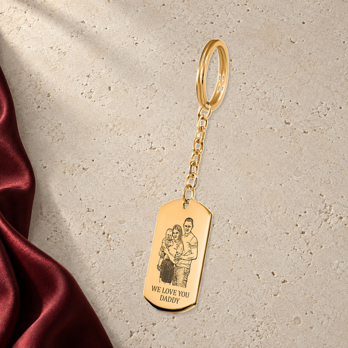 Porte-clés Portrait de Famille Personnalisé en finition dorée sur pierre claire, avec étoffe rouge sanguine ; exemple de personnalisation.